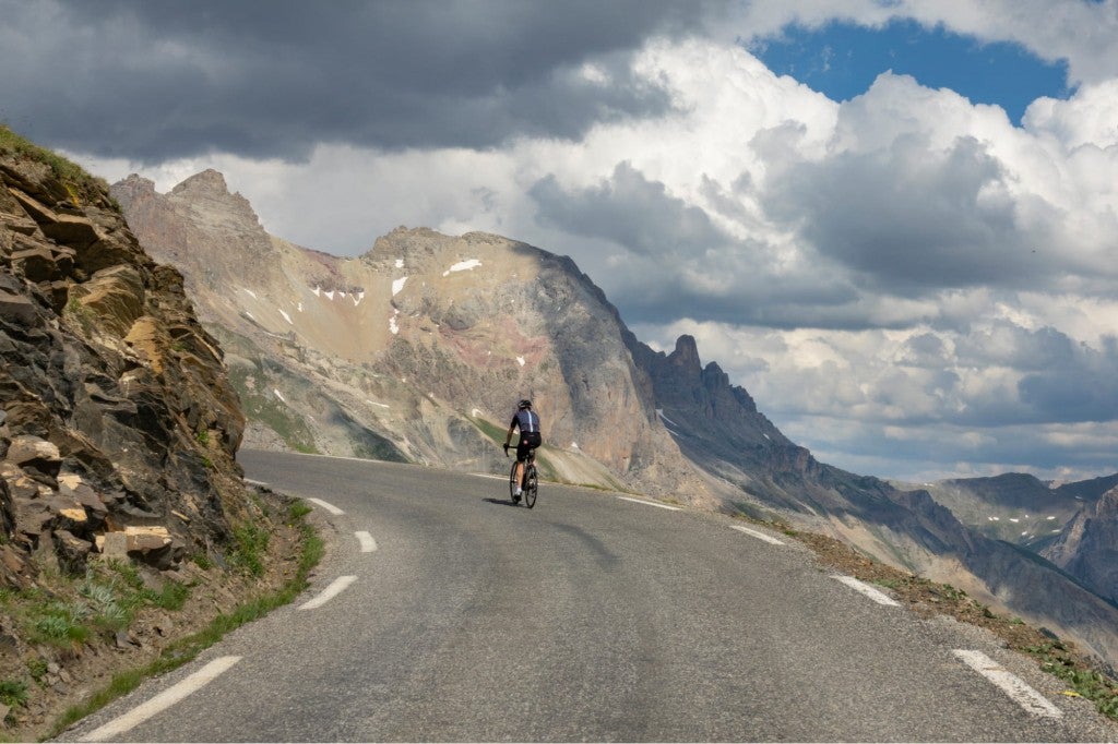 a man riding a bike on a road through mountains