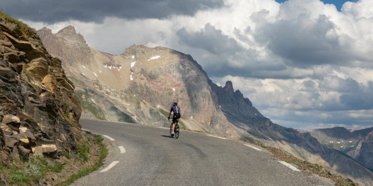 a man riding a bike on a road through mountains