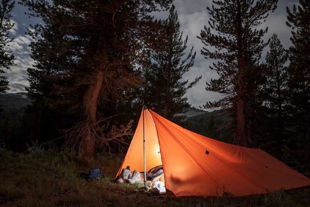 Orange tarp lit up at night in the backcountry.