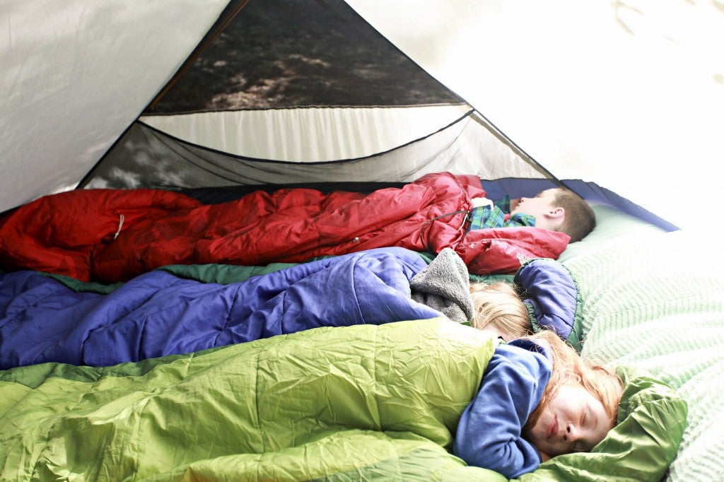 Three kids sleeping in a tent.
