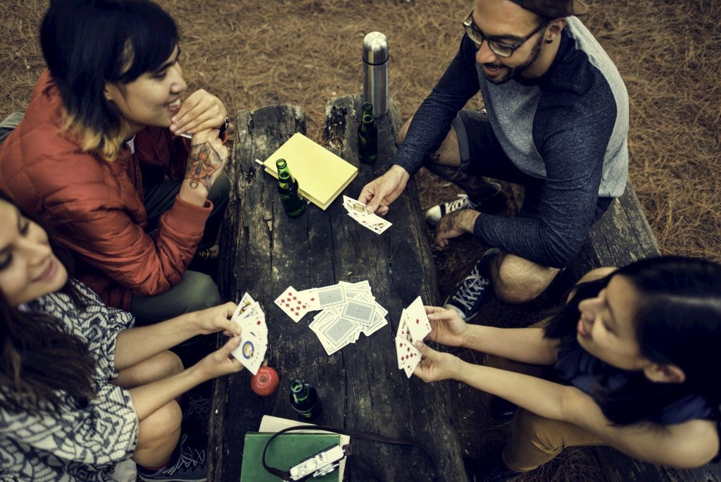 Friends playing cards a round a picnic table.