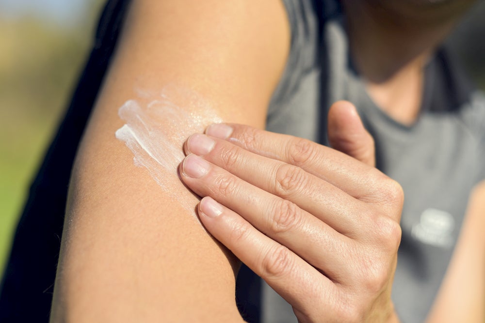 Person applying sunscreen to their arm.