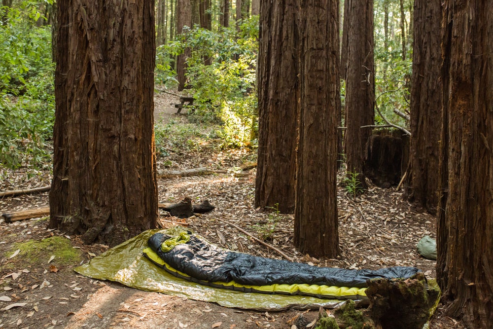 Minimalist campsite of sleeping bag on small tarp.