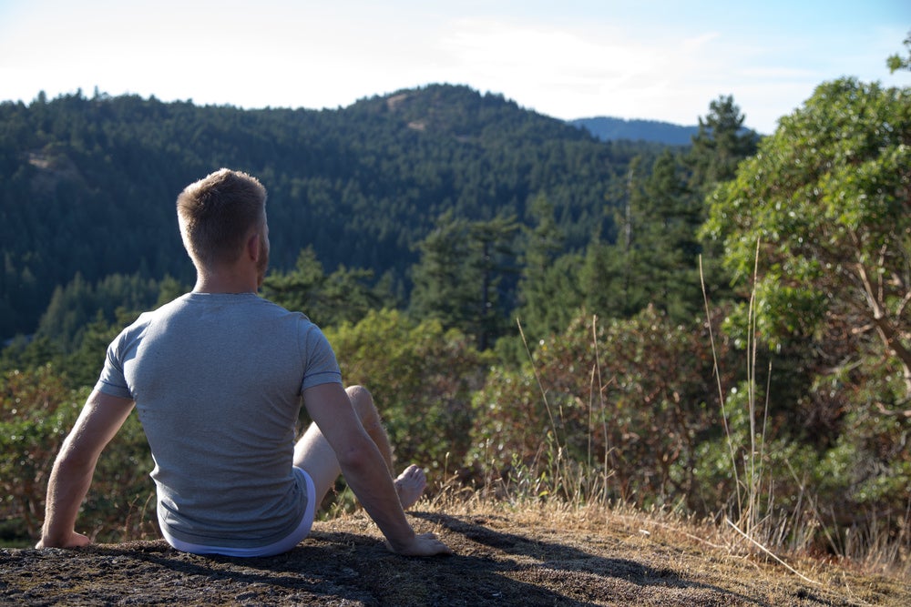 a man sitting on a hill in his underwear outdoors