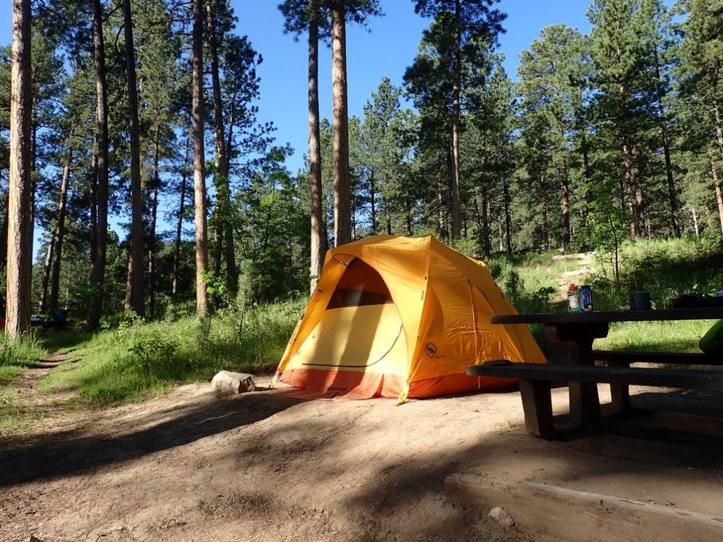 a yellow tent in a campsite in the woods