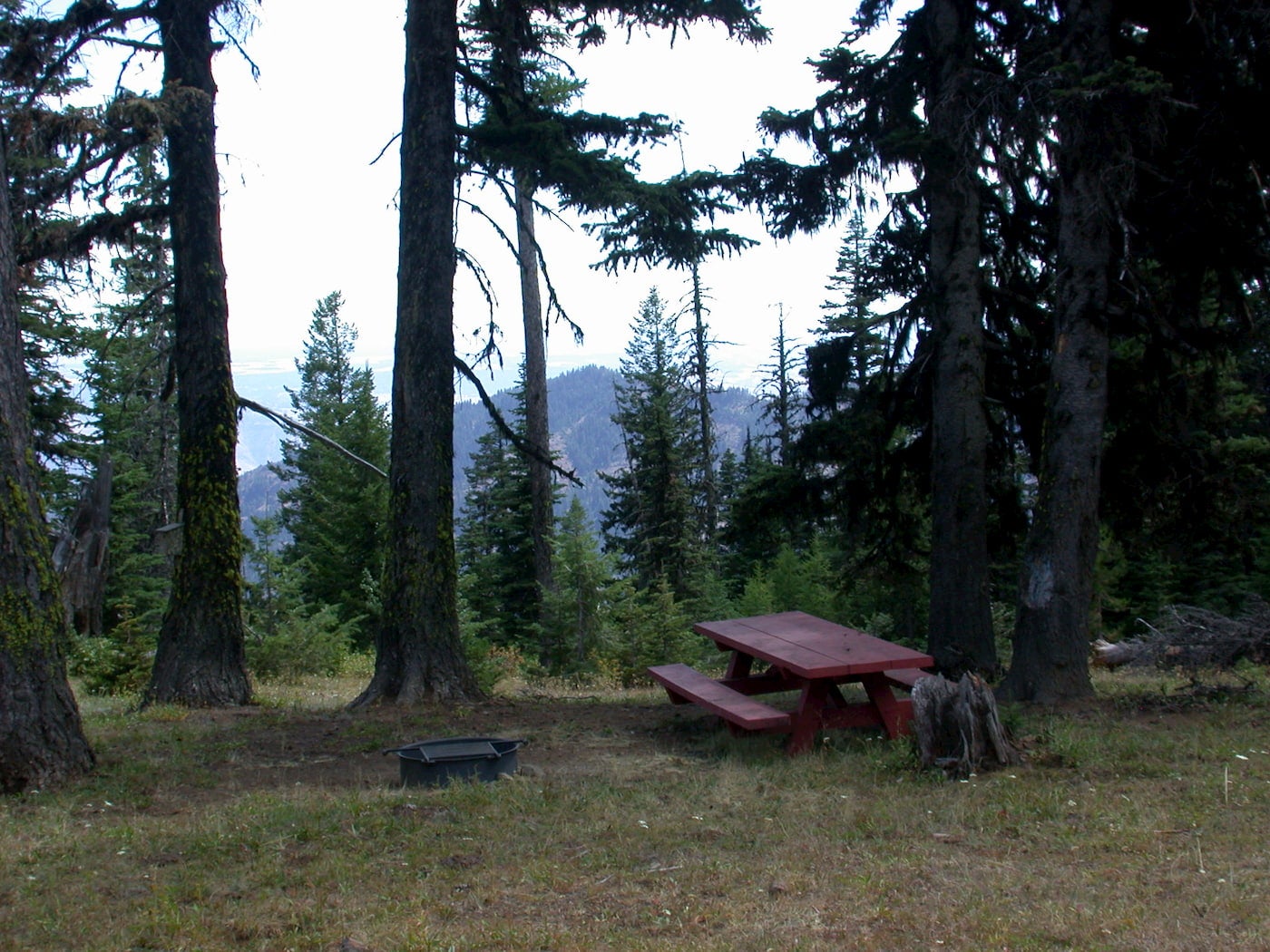 Picnic table and fire pit campsite overlooking hills.