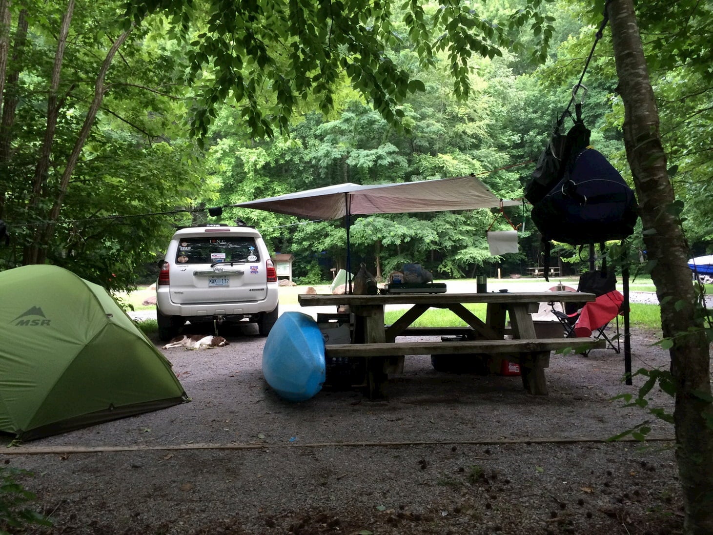 Campsite with tent, umbrella, and kayak,.