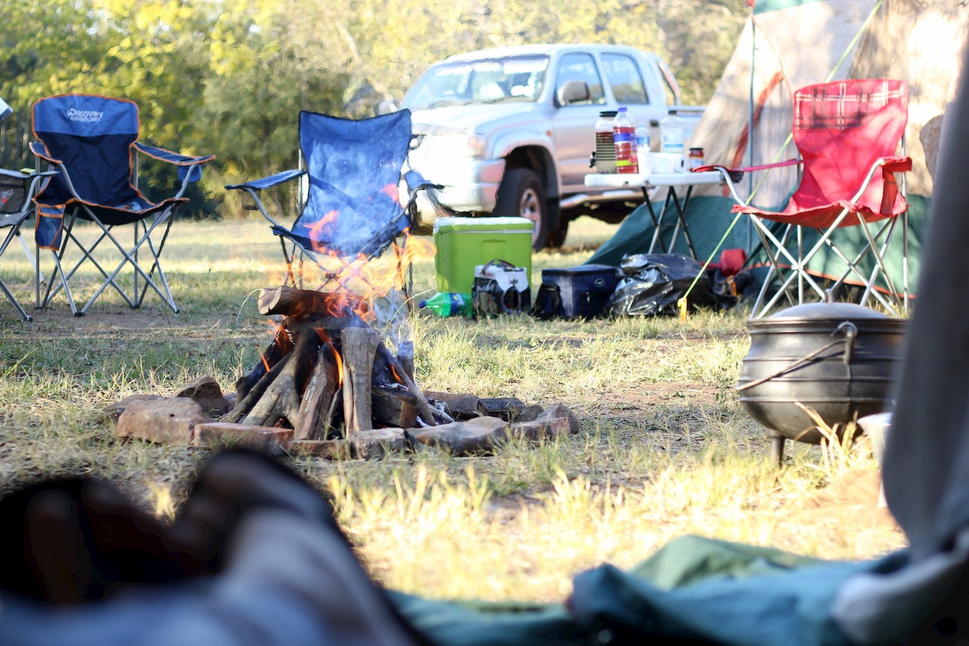 Campsite with chairs and table setup around a campfire.