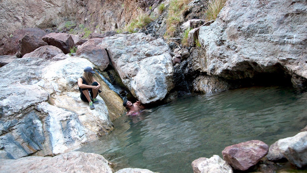 two people in a pool of water in red rocks in nevada