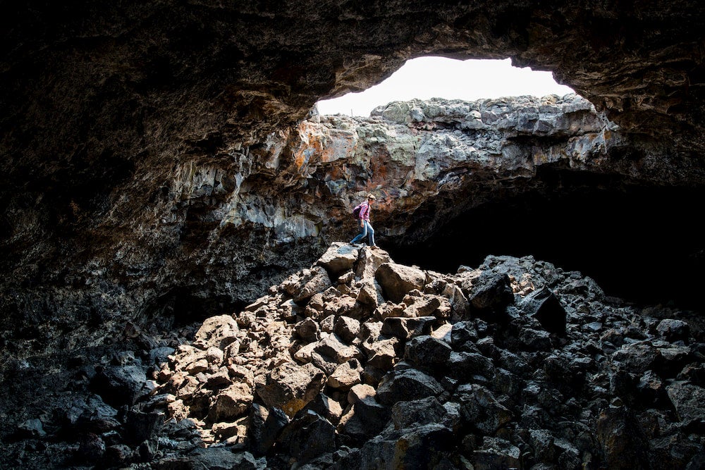 a woman hiking in a cave in craters of the moon idaho