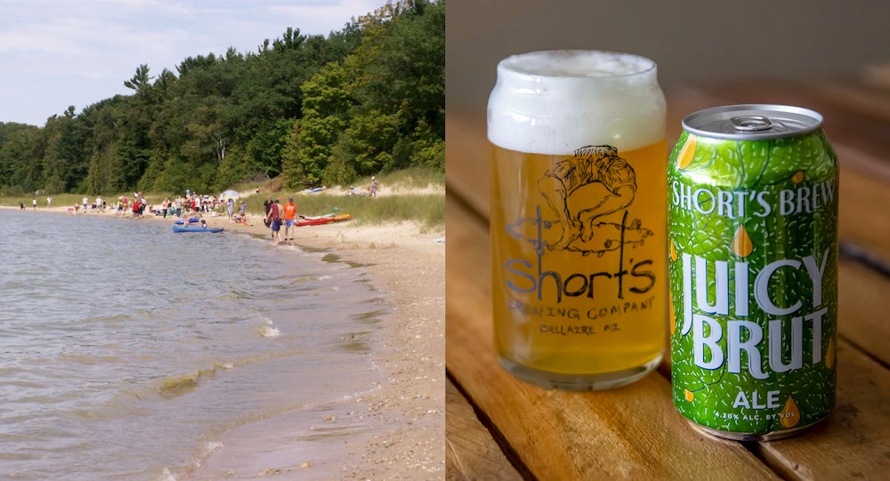 a shoreline on lake michigan next to .a can and glass of beer on a table