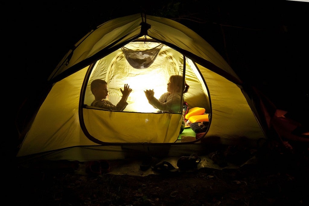 two kids sitting in a glowing tent at night