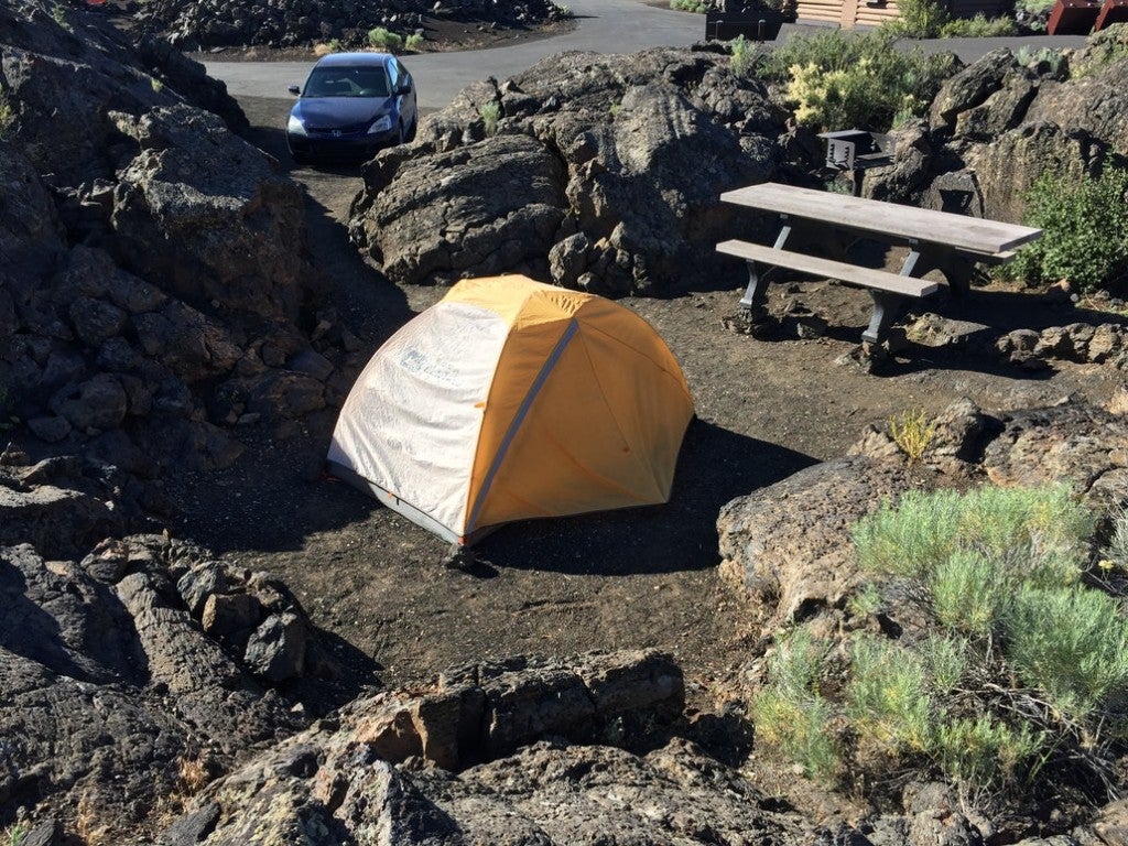 a yellow tent surrounded by lava rocks in craters of the moon idaho