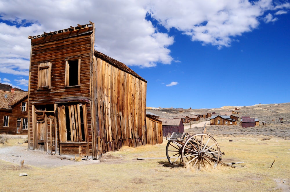 Old abandoned building with carriage and blue sky in background 