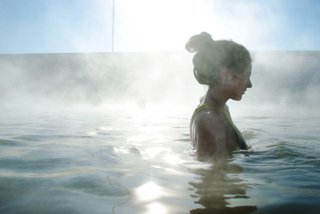 a woman bathes in the mists of a hot spring in california