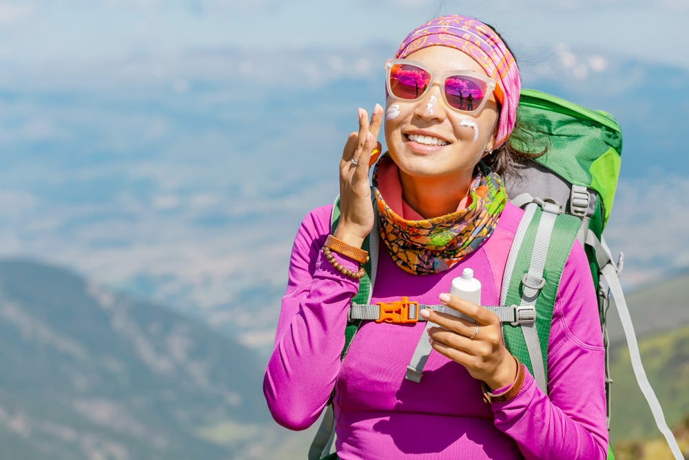 Female hiker applying sunscreen to her face.
