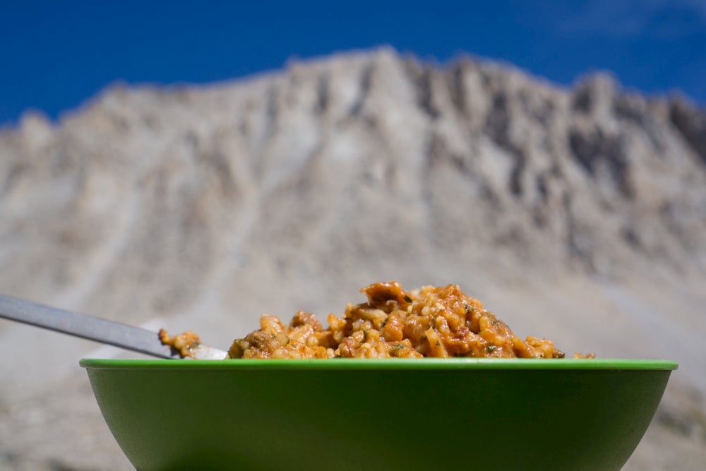 Camping meal in the foreground, mountain in the background.