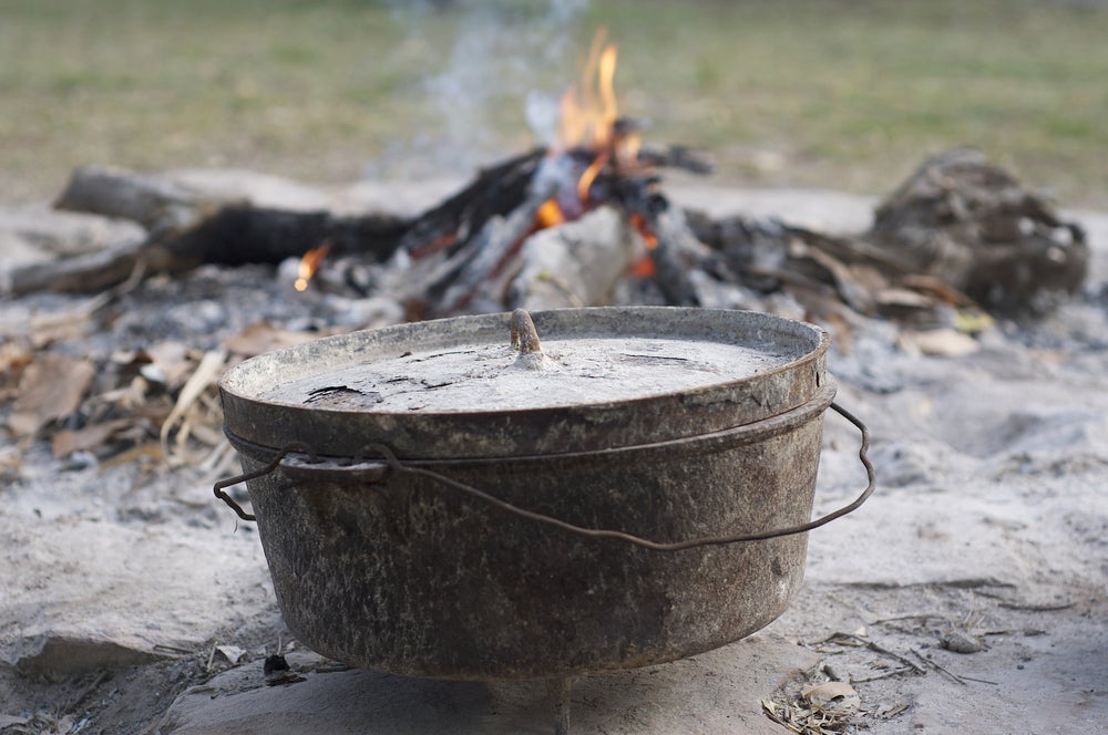 a dutch oven pot near a campfire