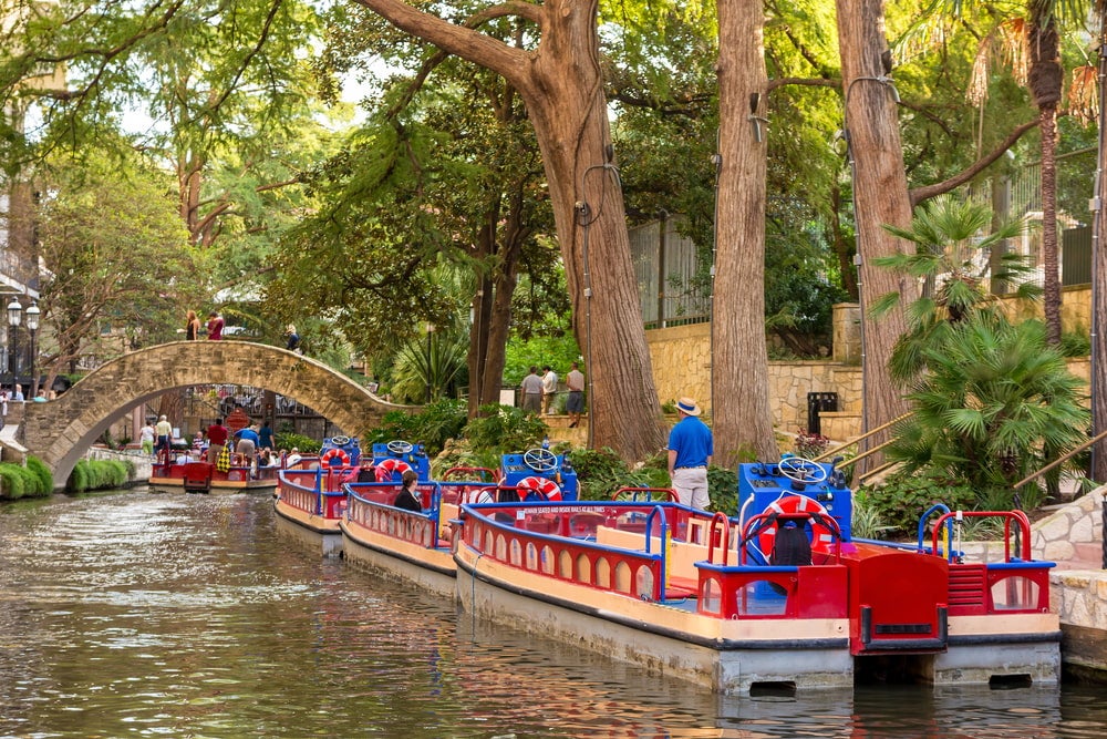 the san antonio riverwalk with boats in a line together 