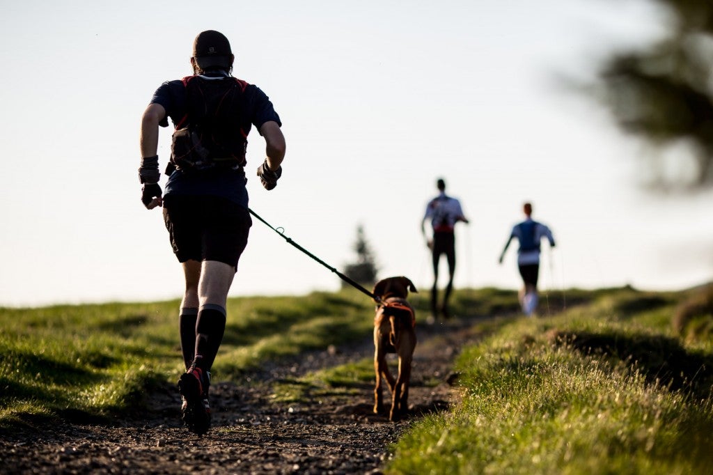 a man running on a trail with a dog