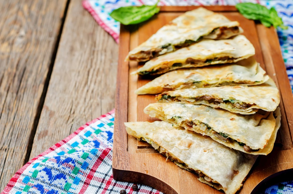 Mushroom quesadillas spread out on wooden platter.