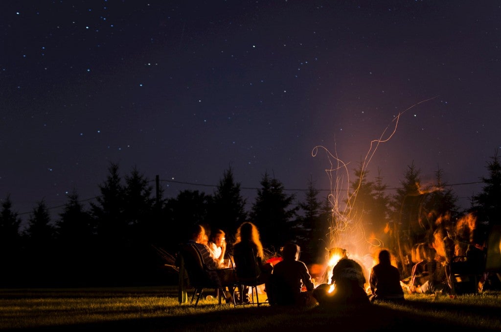 Group of people fathered around a bonfire.