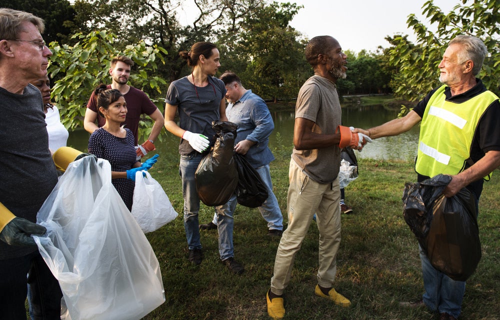 a group of volunteers in a field picking up garbage