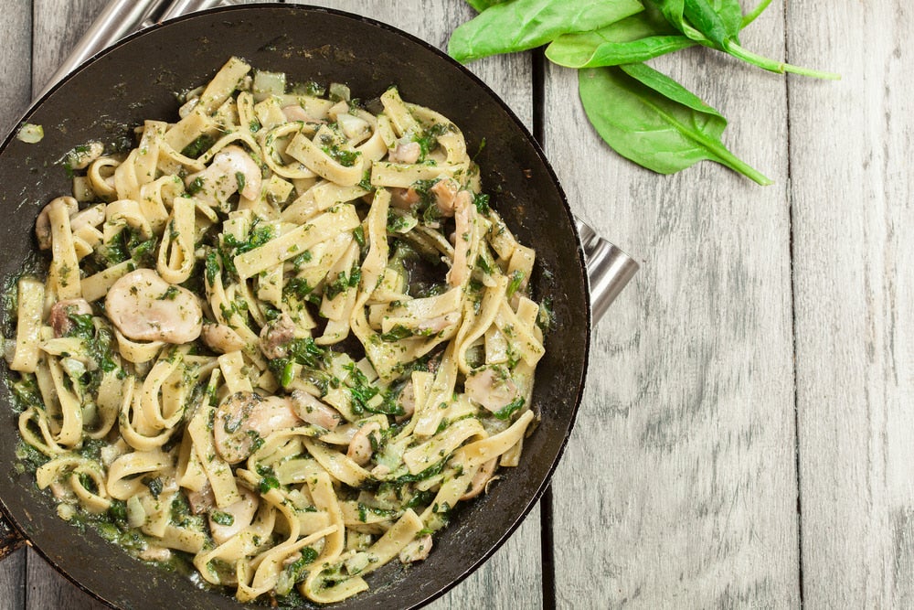 Creamy mushroom pasta garnished with basil leaves.