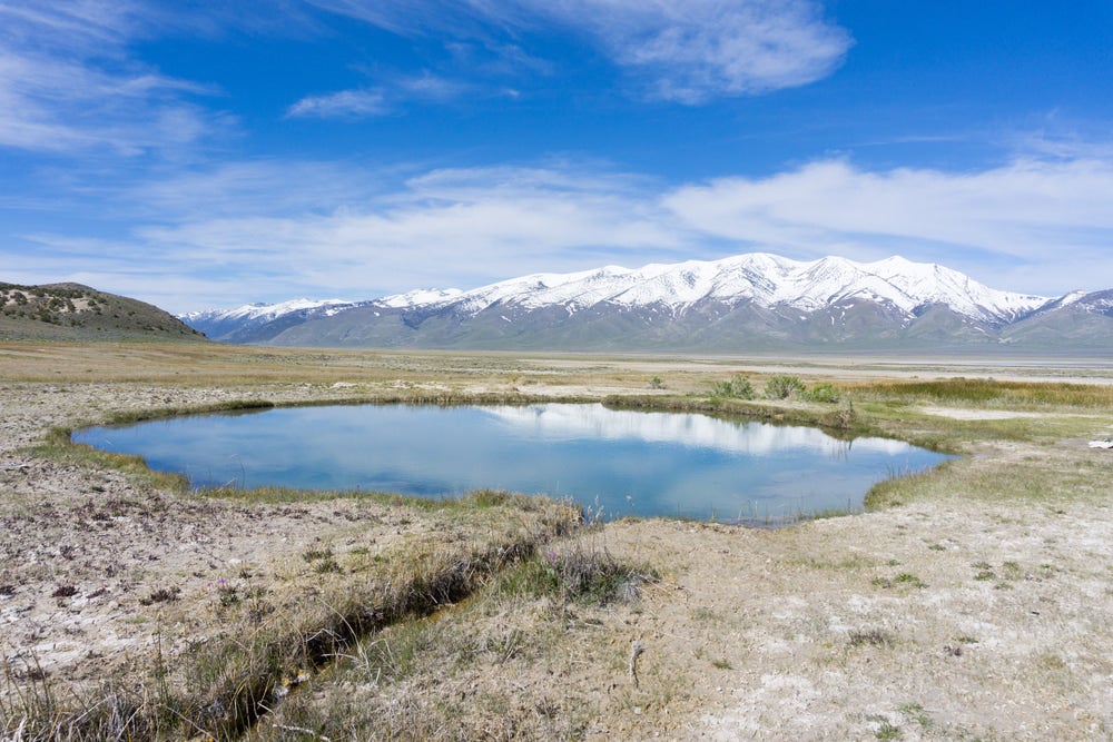 a blue glacial pool in the desert near the mountains