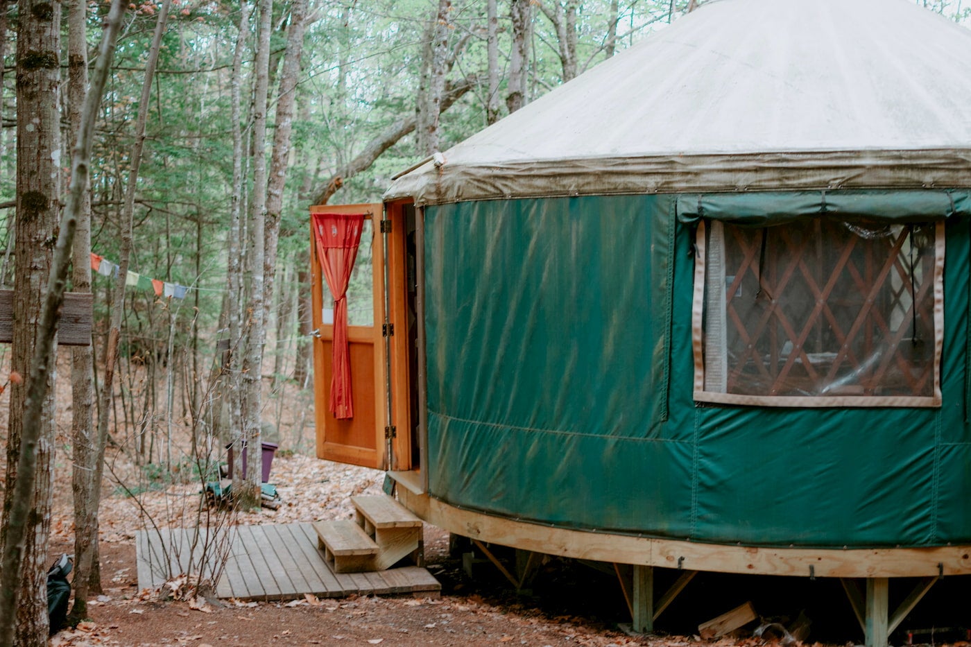 Green yurt with wooden steps up to it.