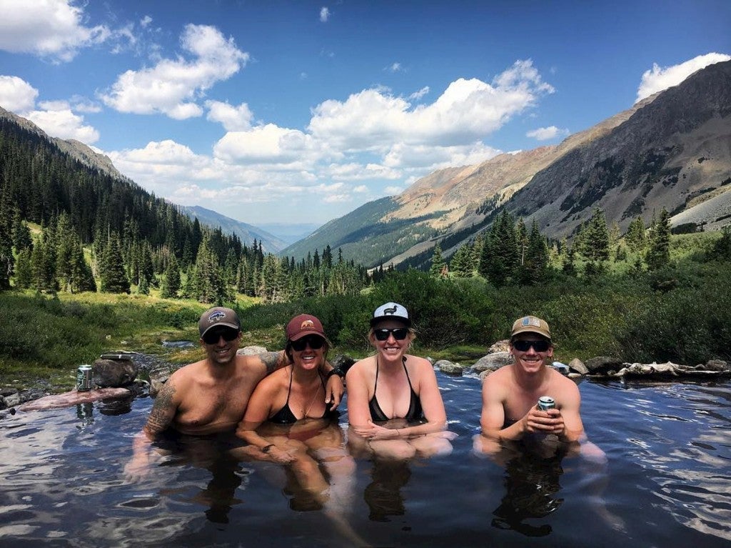 Group of four backpackers hanging out in hot springs.