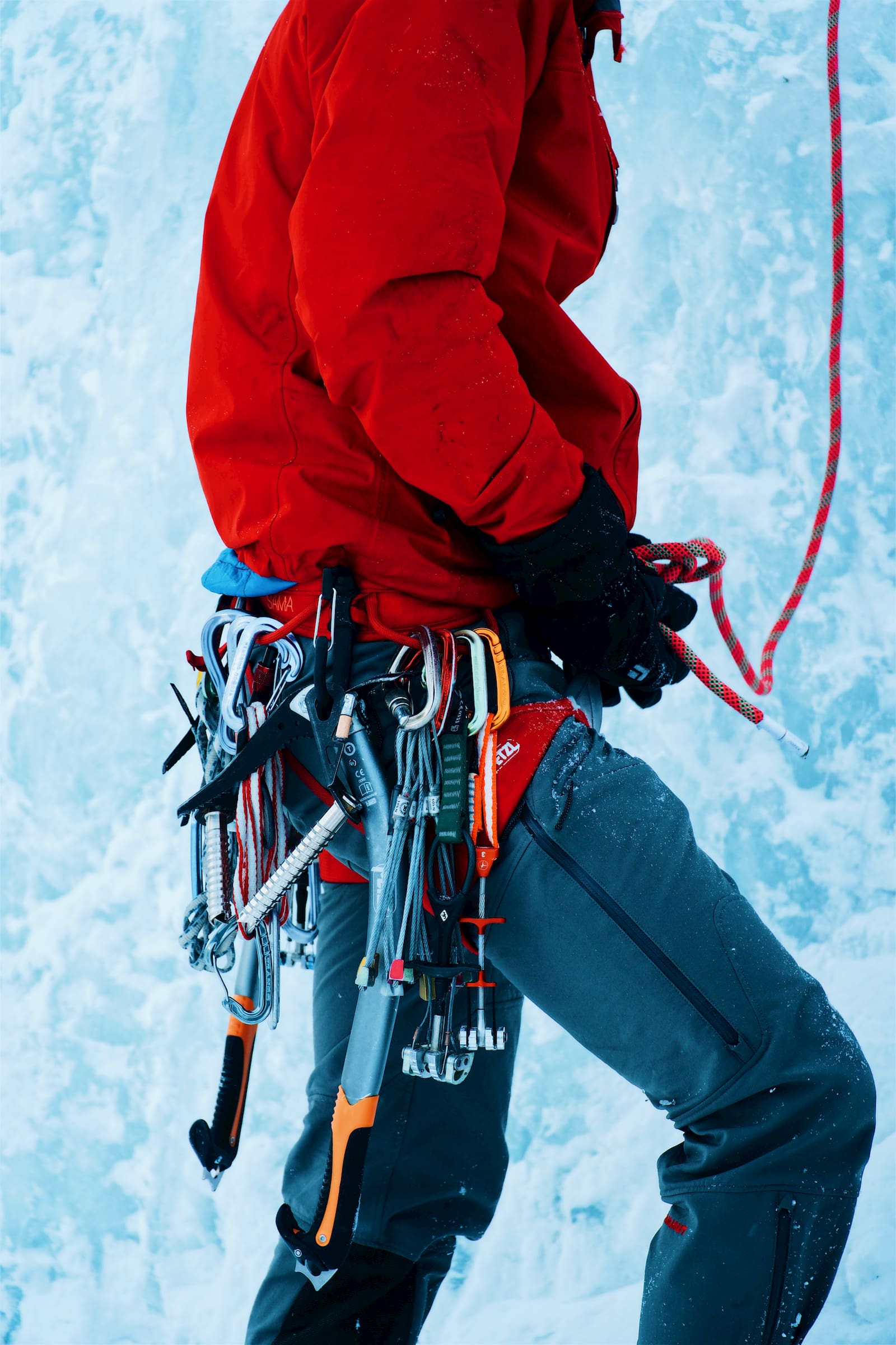 Ice climber with tons of trad gear, quick draws, and ice axes on their harness.