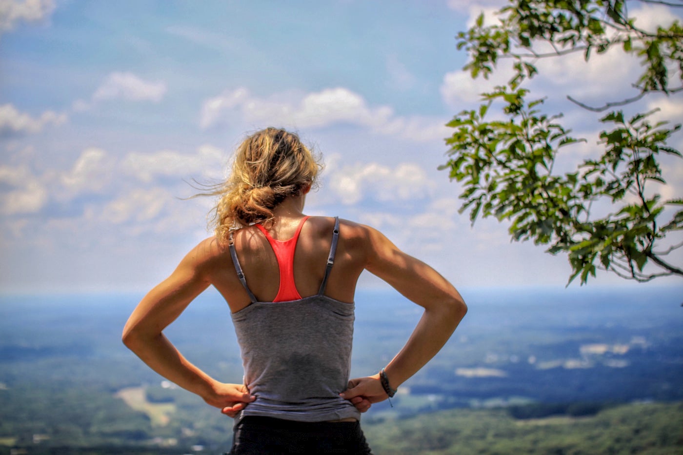 Woman catching her breathe at the top of a hill after running.