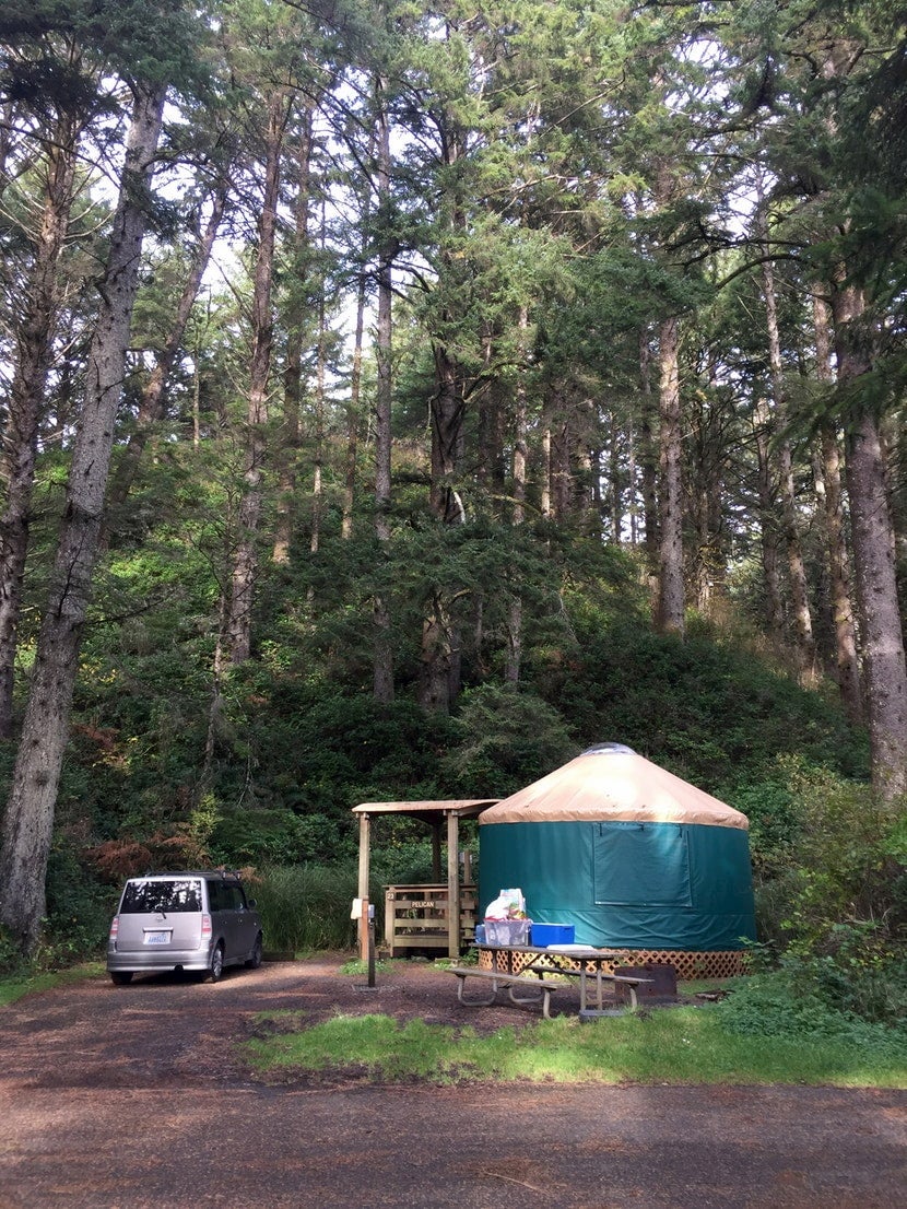 Oregon yurt in the woods beside a parked car.