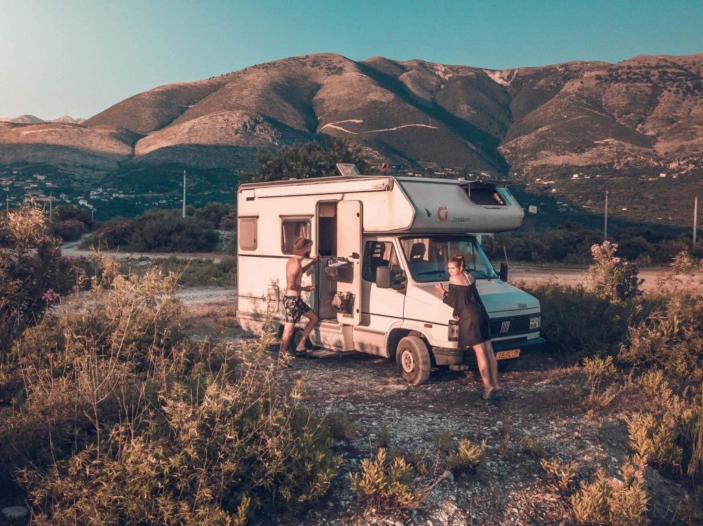 Young couple hanging outside their camper R.V. in a high alpine prairie.