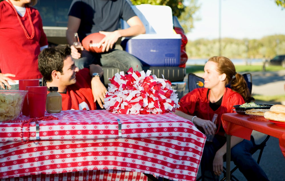 People sitting around table with tailgating supplies.