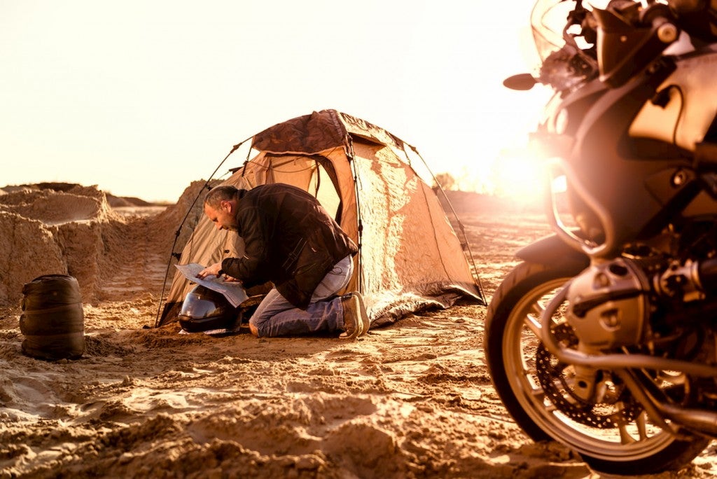 Motorcycle camper packing up tent.
