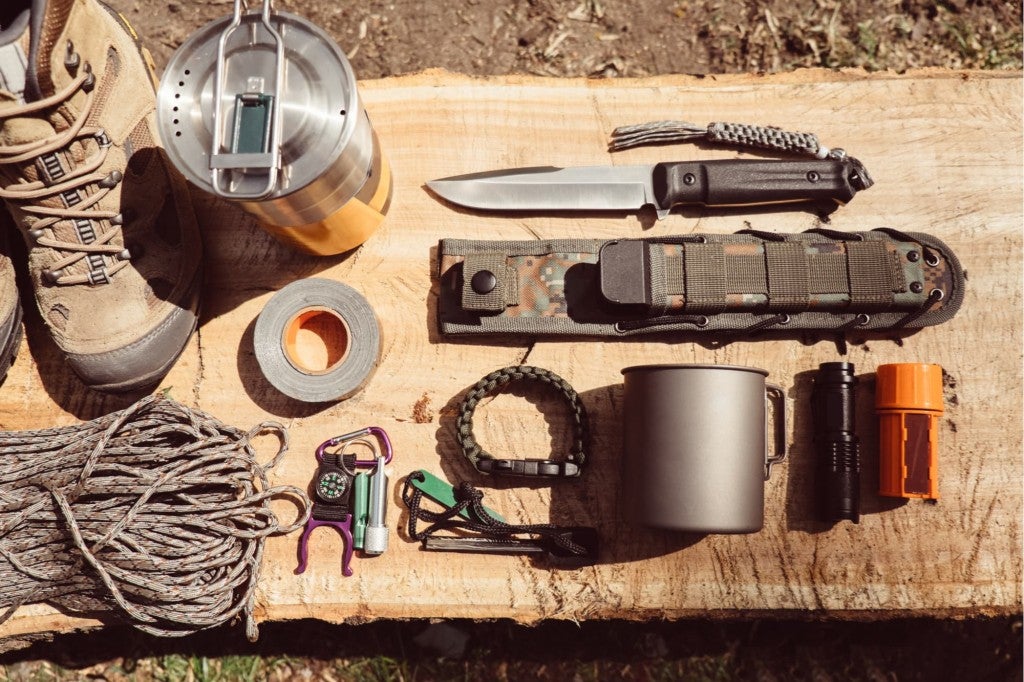 a survival tool gear pack laid out on a log in the wilderness