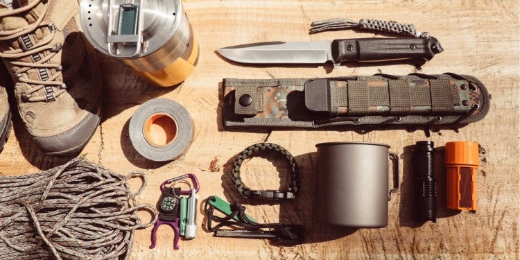 a survival tool gear pack laid out on a log in the wilderness