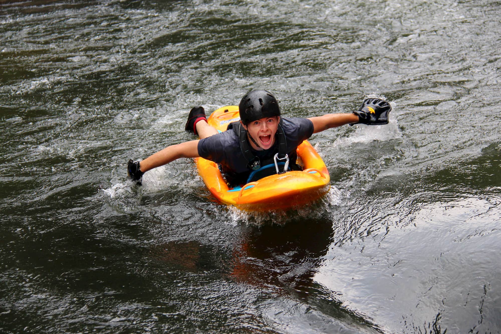 a man smiling and paddling down a river