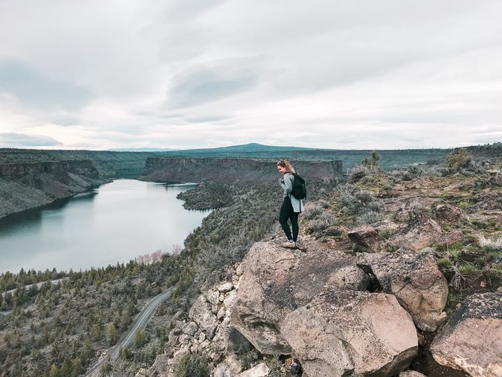 woman standing on a rock with a canyon and water below 