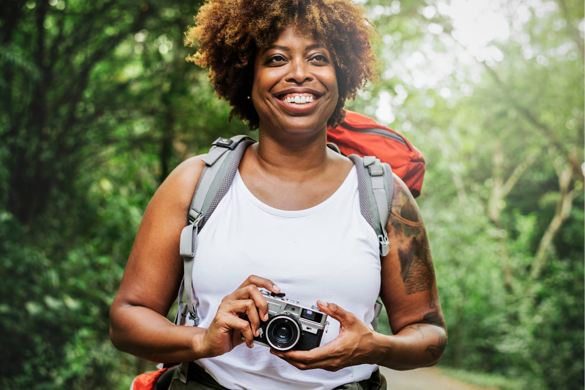 a woman holding a camera with a hiking tattoo