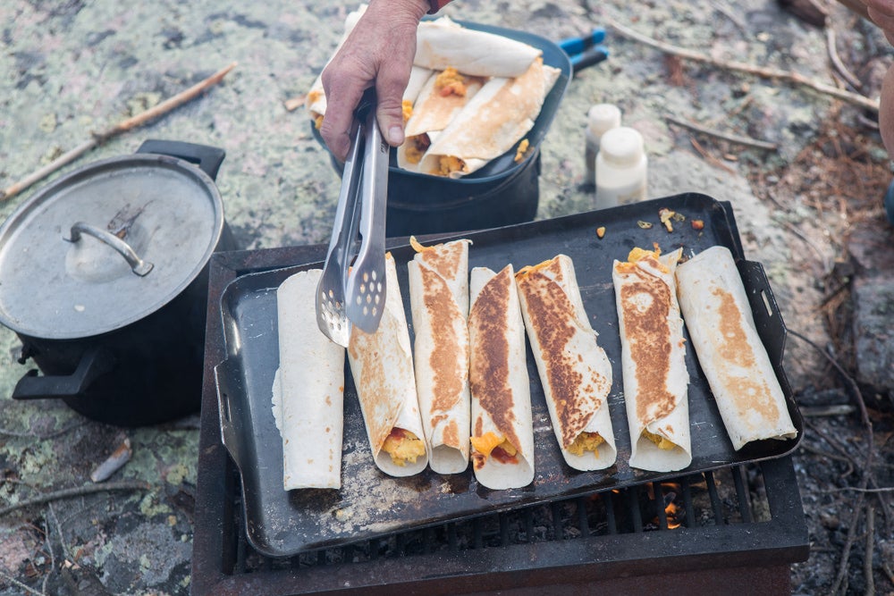 a grill cooking burritos while camping