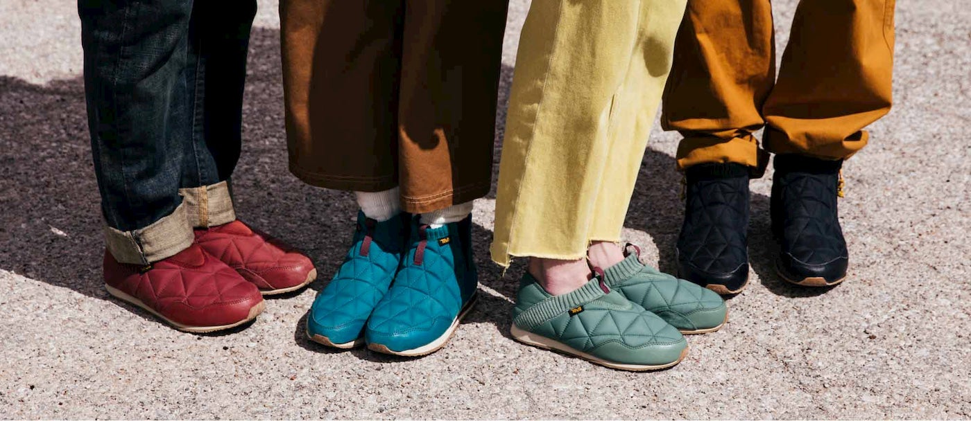 Group of people's legs and feet wearing colorful slippers.