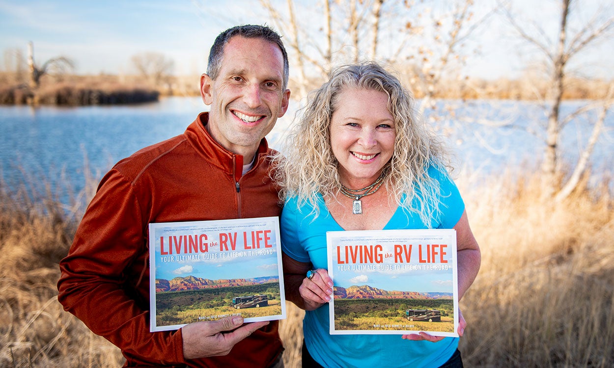 Authors of Living the RV Life holding the published book outside.