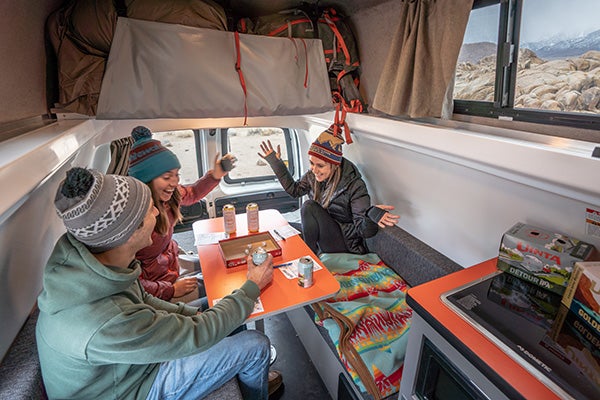 Group of three people playing a game in a travellers autobarn van.