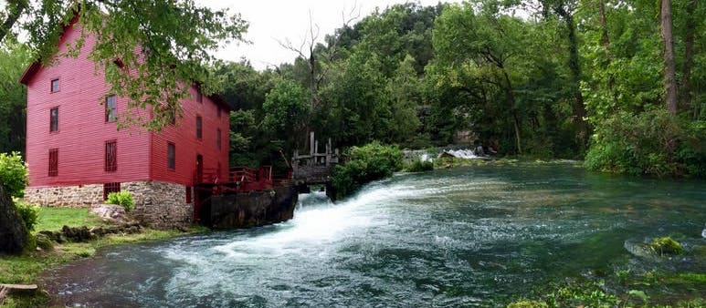 red house next to wide river surrounded by trees