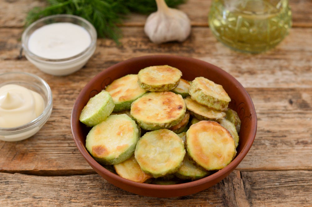 Fried zucchini in a bowl on a wooden table.