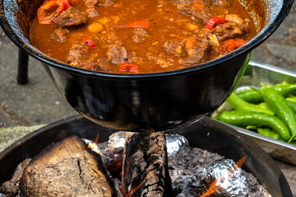 Beef stew cooking over a fire.