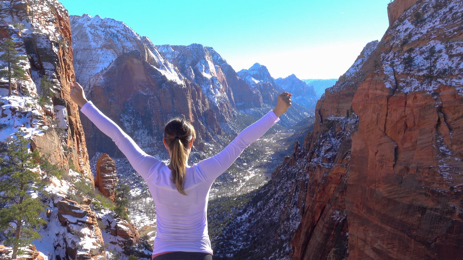 woman with arms raised in celebration in Zion National Park in winter